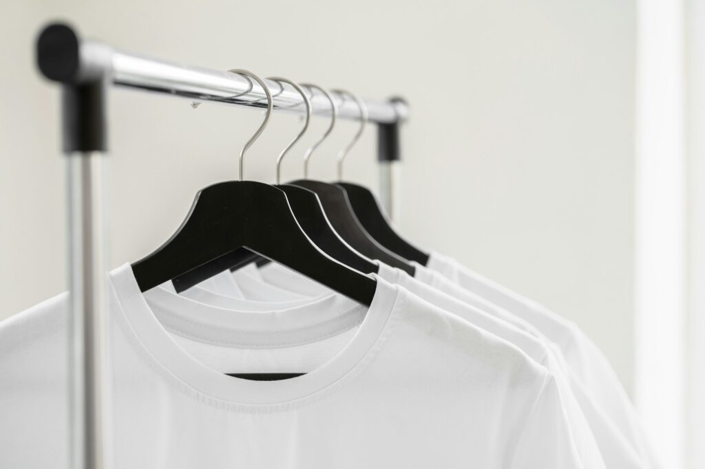 Row of white t-shirts on hangers on rack